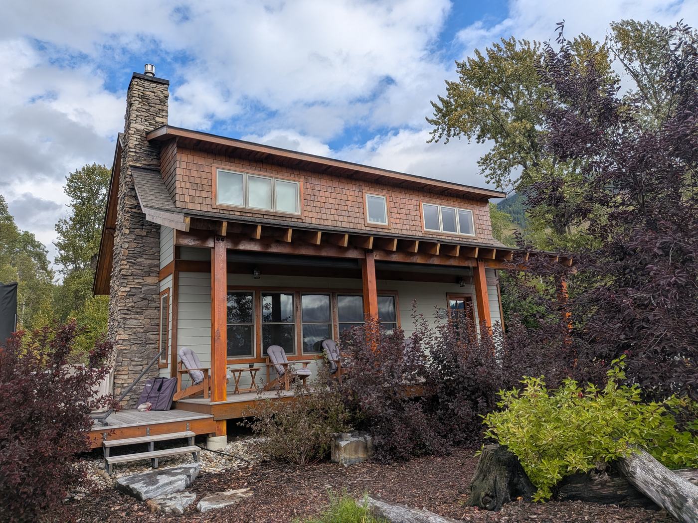 Cottage with stained shake siding, stone chimney and covered porch