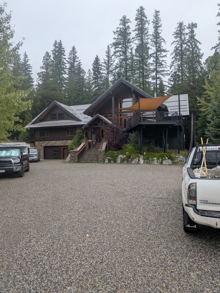 Large timber lodge-style home in the trees with a gravel drive